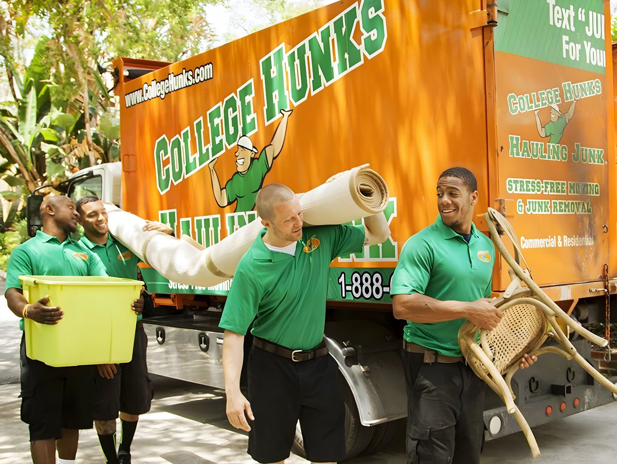 College H.U.N.K.S. moving team carrying furniture beside an orange branded truck